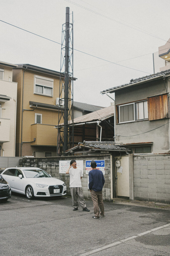 焚の建物の煙突を見上げる川良さんと光川